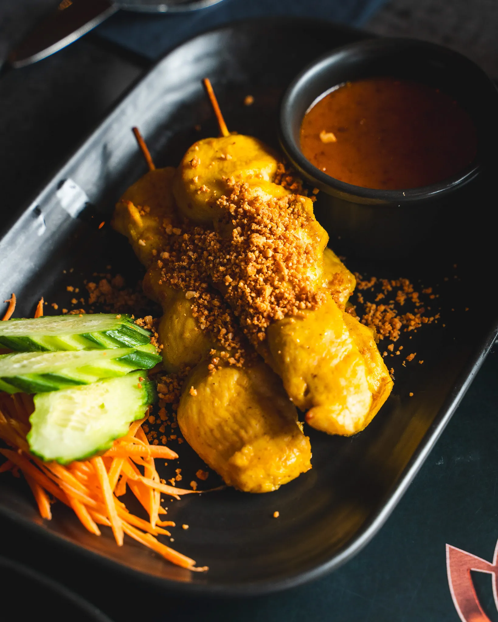 Golden satay skewers with peanut sauce and fresh cucumber.