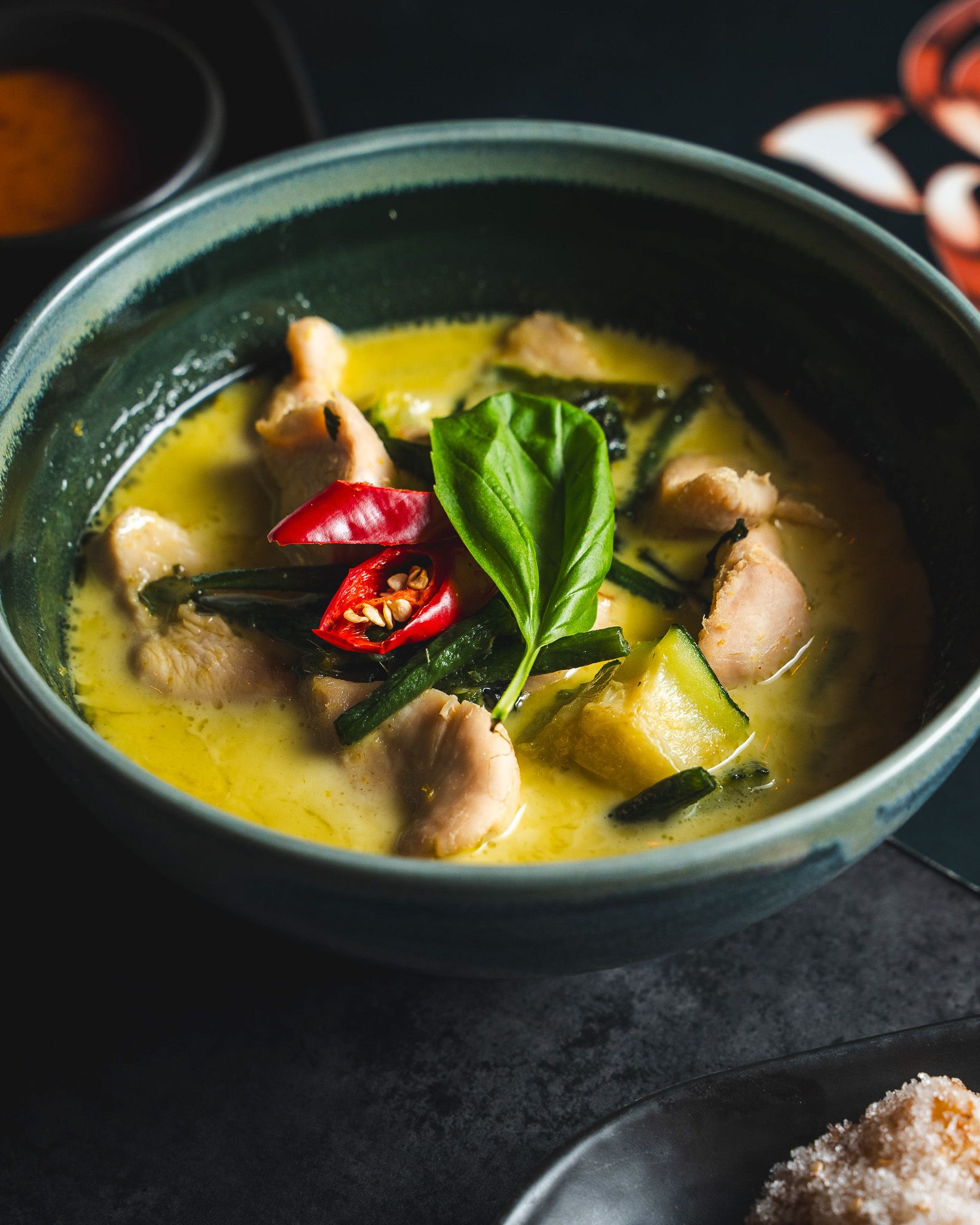 Green curry topped with basil and sliced red chilli.