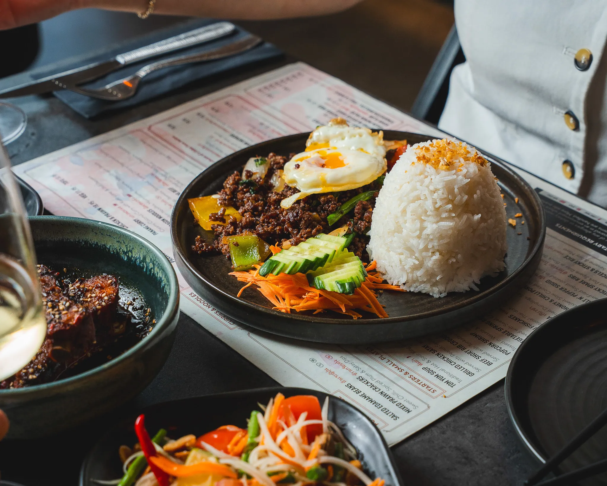 Stir-fried beef with rice, a fried egg and fresh vegetables.