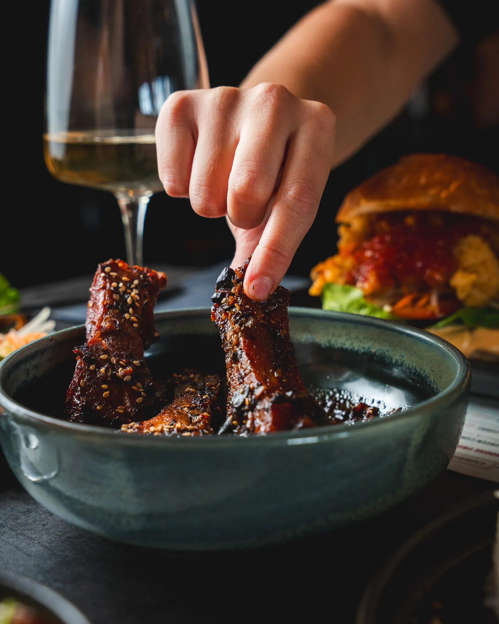 A guest sharing glazed ribs across the table.