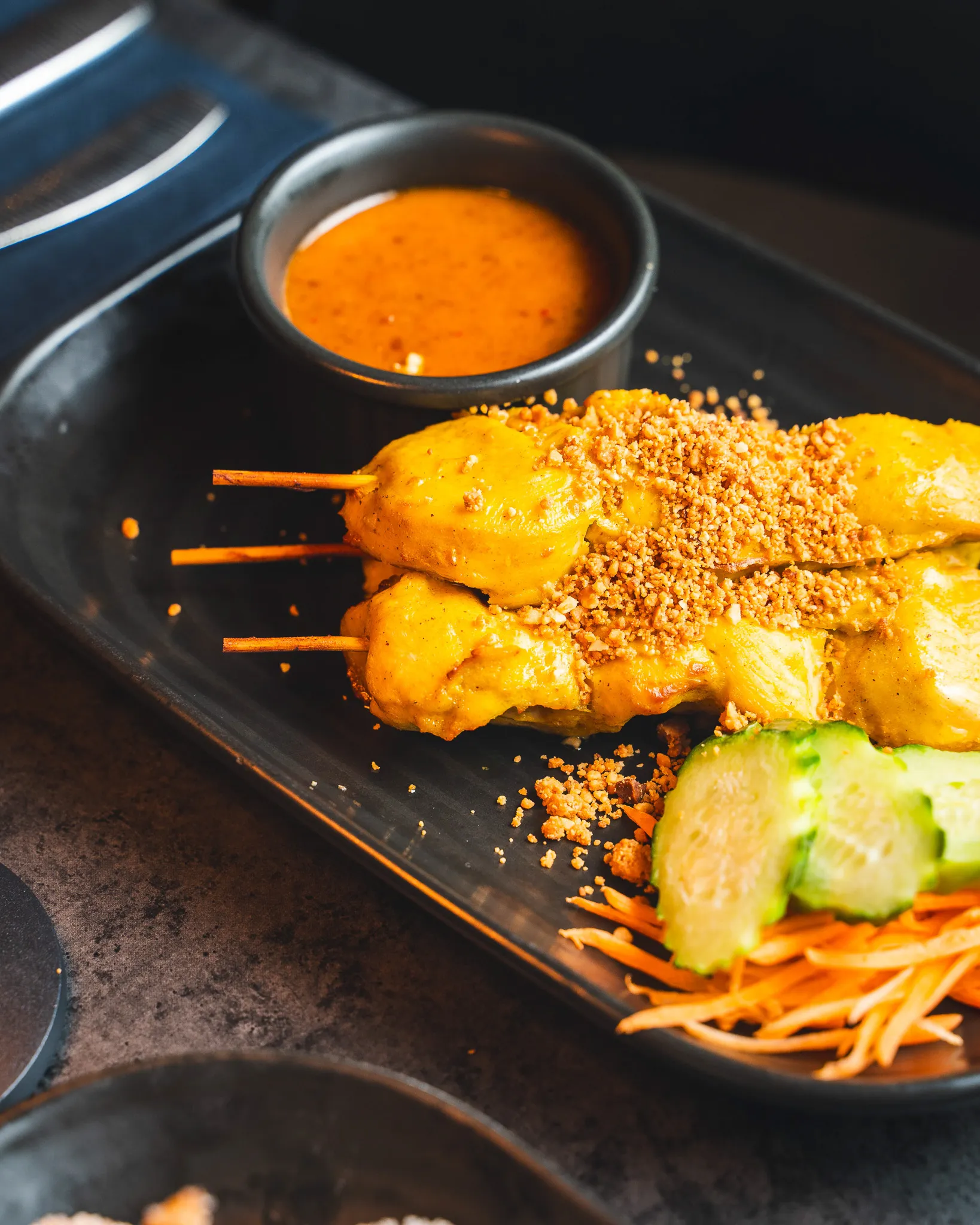 A close-up of satay skewers with peanut sauce.