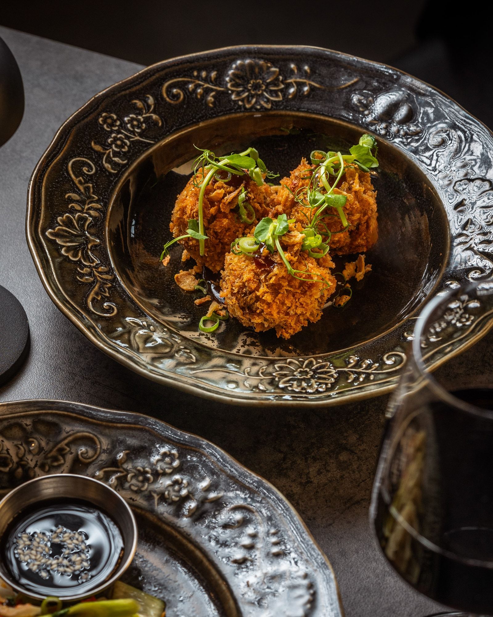 A plate of crisp golden bites garnished with herbs and sauce.