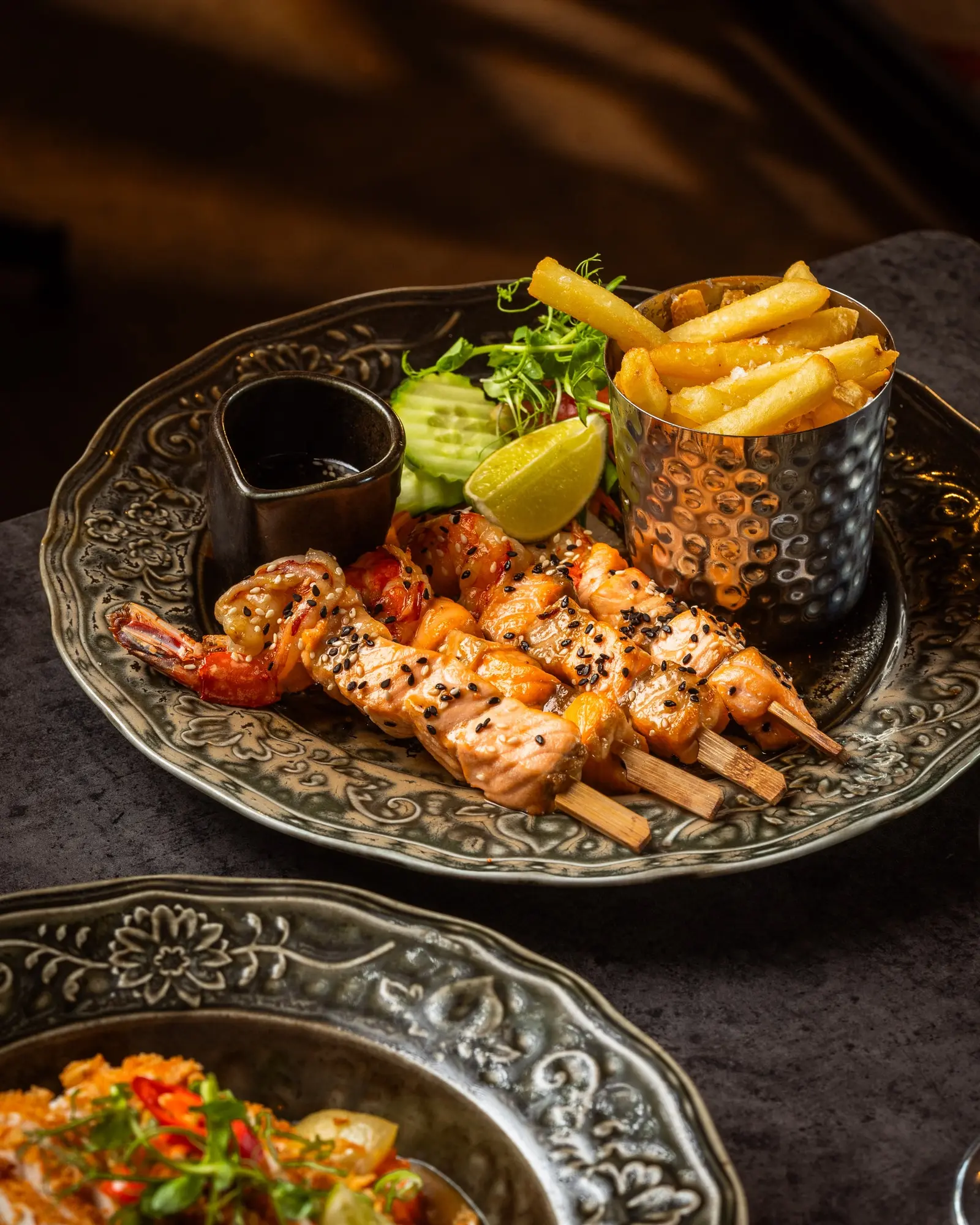 Seafood skewers with fries, salad, lime and dipping sauce.